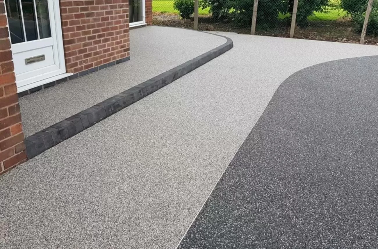 Curved pale resin path defining an approach to a brick house