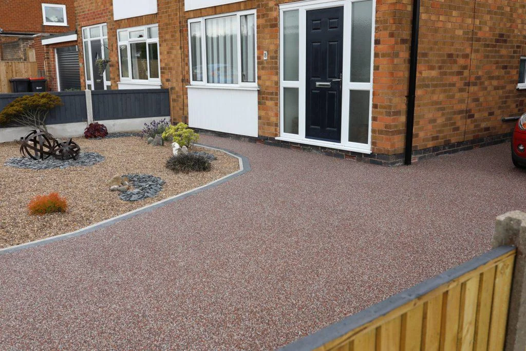 Warm-toned resin patio beside a conservatory and brick house